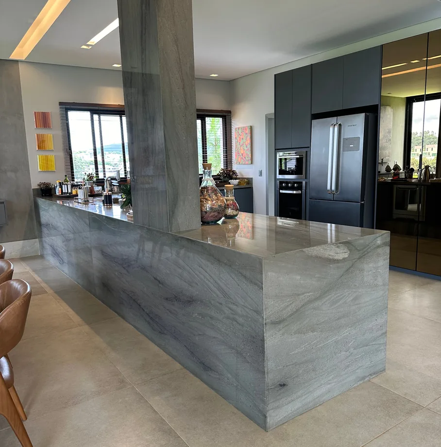 Ilha de cozinha revestida em quartzito cinza-azulado, com o veio seguindo da bancada para a lateral.